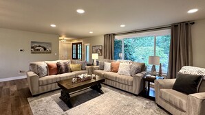 Ein großzügiges Wohnzimmer mit zwei Sofas, einem Couchtisch und einem großen Fenster mit Vorhängen.