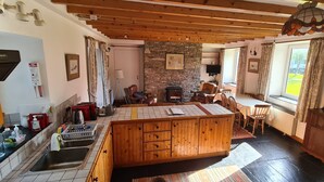 Una cocina acogedora con una isla central, armarios de madera, una pared de piedra y un comedor con sillas y una mesa.
