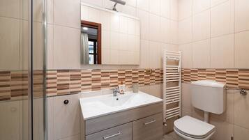 Un bagno con lavandino bianco, un water, uno specchio e un portasciugamani.