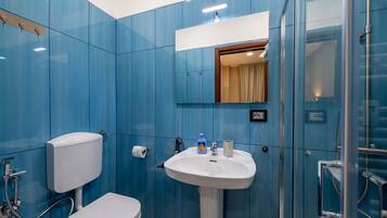 Baño con inodoro, lavabo y ducha.