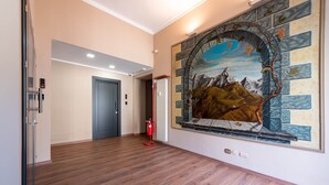 Un couloir doté d’un plancher en bois, d’une porte bleue et d’une fresque représentant un paysage de montagnes et une rivière.