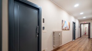 Un couloir avec des portes sombres, un radiateur et un extincteur.