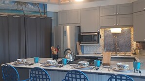 Una cocina moderna con armarios grises, un refrigerador de acero inoxidable, un microondas y un salpicadero azulejado.