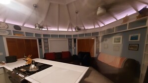 Una cocina compacta con una isla central, un área de comedor con sofá y un ventilador de techo.