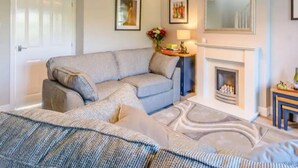 A modern living room with a grey sofa, a fireplace, and framed artwork on the walls. - Stunning 2-bed House in Walkington Near Beverley (Beverley)