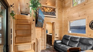 Un intérieur en bois avec un canapé en cuir noir, une table à manger et un escalier.