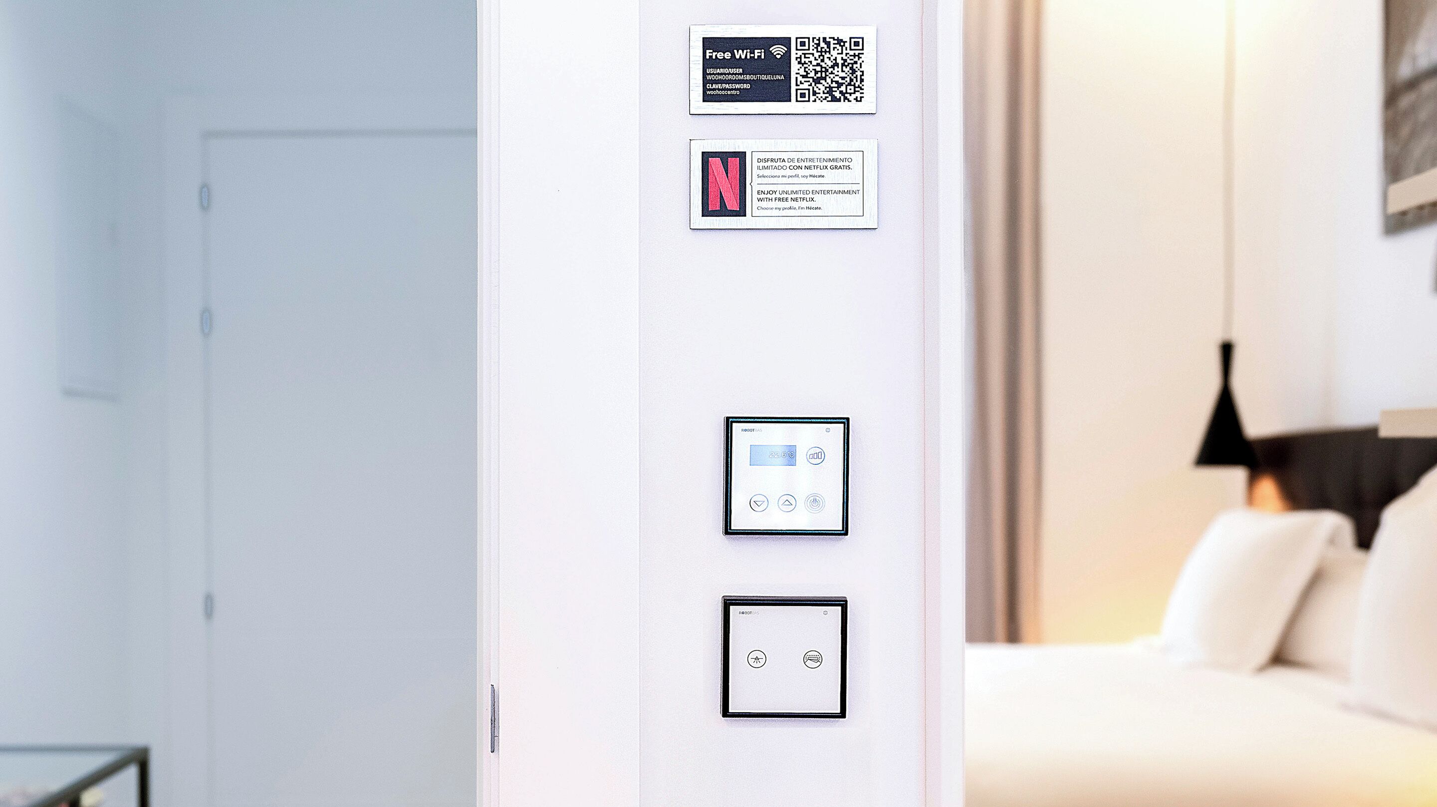 Un mur avec un code QR, un panneau indiquant que le Wi-Fi est gratuit, et un panneau de commande pour le thermostat.