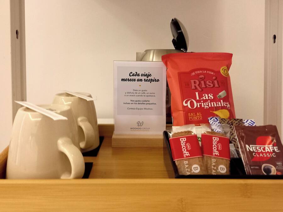 A tray with a white teapot, a red bag of Risi Las Originales coffee, and several boxes of Nescafe Classic and Biscoff chocolate bars.