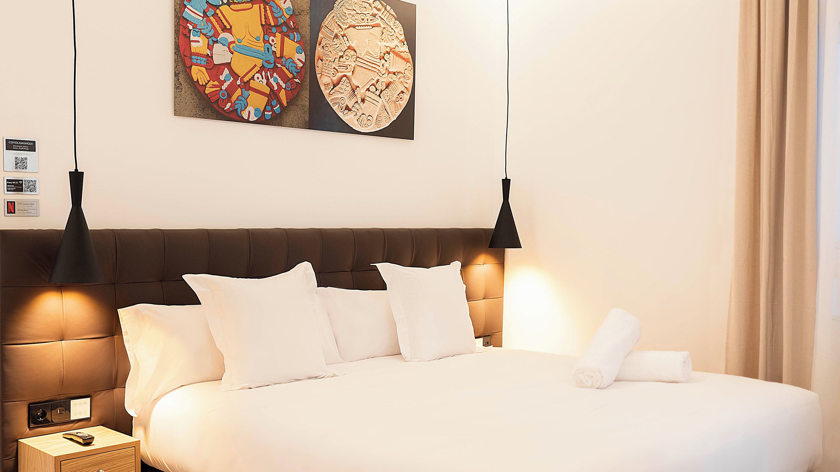 A hotel room with a large bed, two bedside lamps, a nightstand, and a wall-mounted artwork.