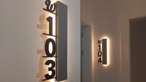 Un pasillo moderno con letreros iluminados que indican los números de habitación 103 y 104.