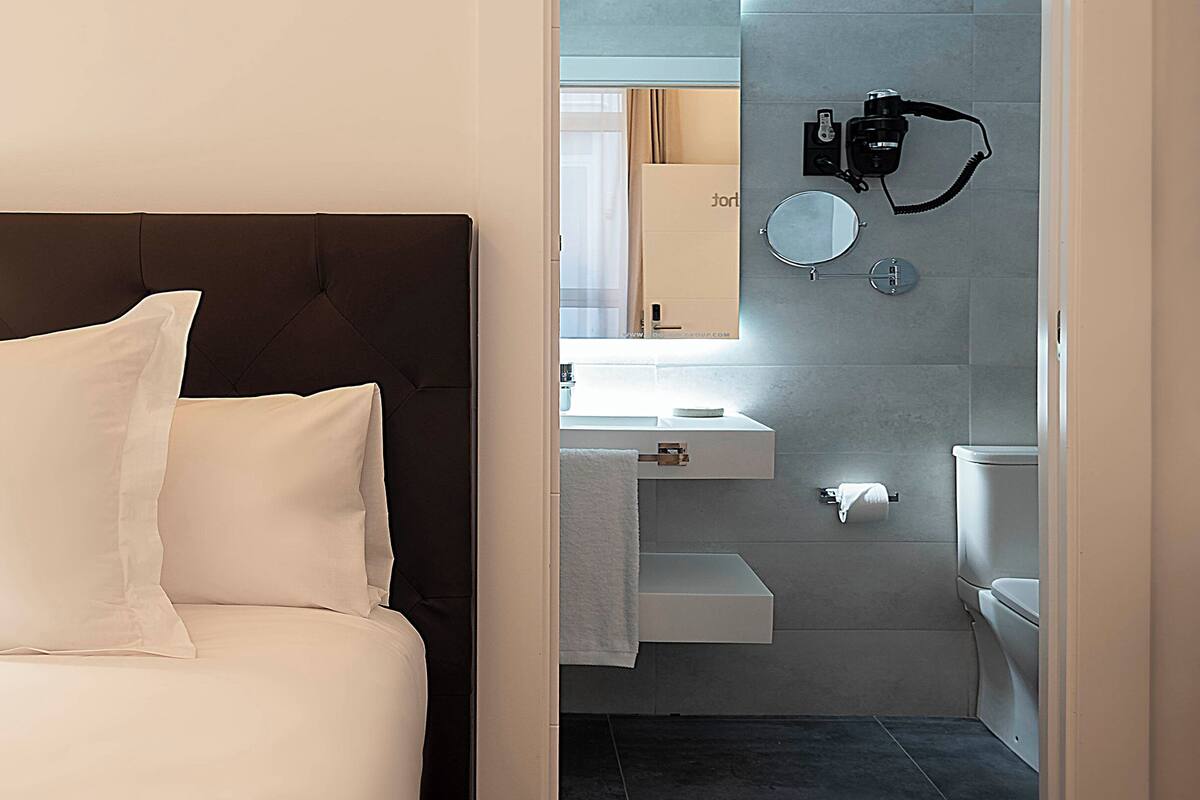 Een hotelkamer met een bed, een badkamer met wastafel, spiegel en toilet.