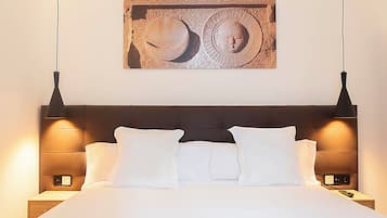 A neatly made bed with white linens and pillows, a dark headboard, and two bedside lamps.