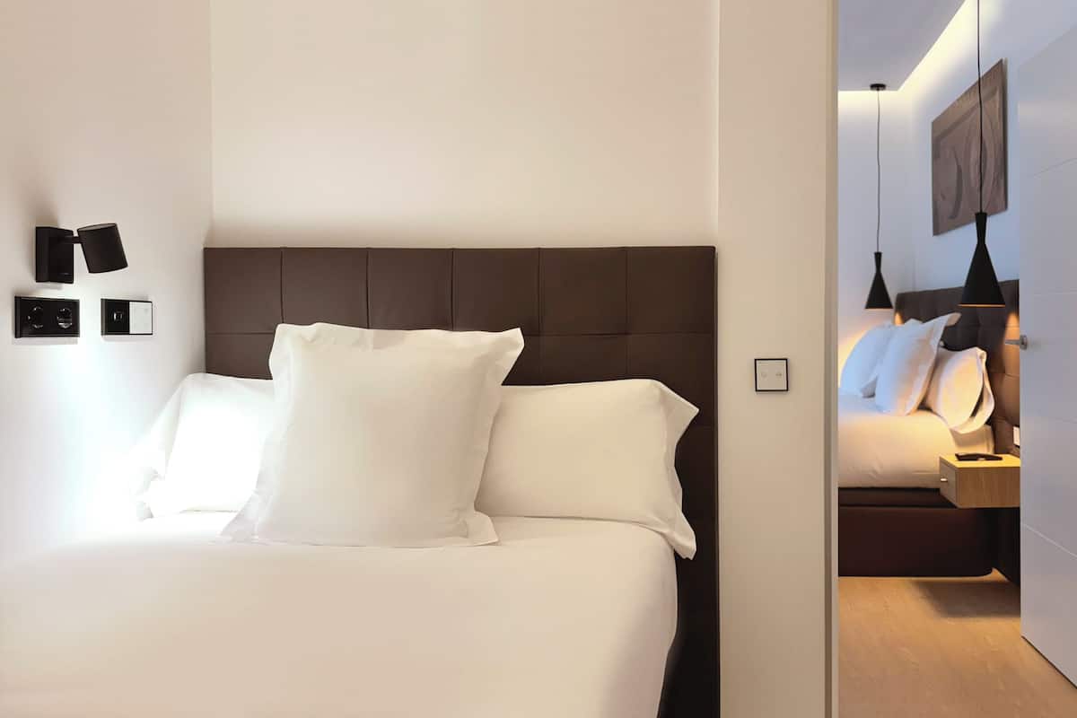 Een moderne hotelkamer met een groot bed, een hoofdeinde, nachtkastjes en wandlampen.