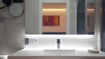 Un baño moderno con un lavamanos blanco, un espejo y un teléfono instalado en la pared.