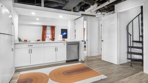 A modern kitchen with white cabinets, a built-in dishwasher, and a colorful rug. - 5bd Vibrant Haven: Basketball - 10mins to Airport (Charlotte)