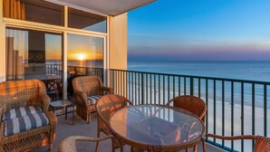 A balcony with wicker furniture and a glass table overlooking the ocean at sunset. - Sunset Views, Gulf Front at Jade East Towers (Destin)