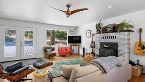 A spacious living room with a fireplace, a television, and a guitar. - Cozy home on private acreage,
 with a short walk to downtown Leavenworth. (Leavenworth)