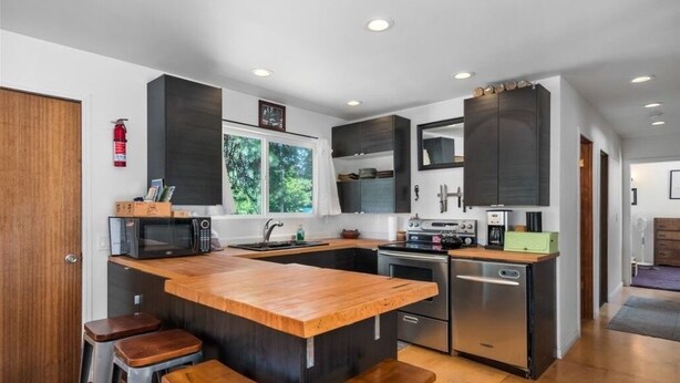 A modern kitchen with a central island, stainless steel appliances, and wooden stools. - Cozy home on private acreage,
 with a short walk to downtown Leavenworth. (Leavenworth)
