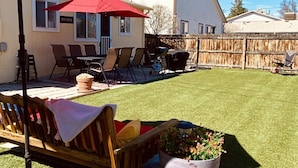 A backyard with a wooden bench, a red umbrella, and a potted plant. - The Mulberry House for Fun in Fruita (Fruita)