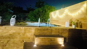 Une terrasse en bois avec une piscine, des marches et des guirlandes lumineuses.