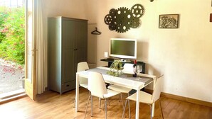 Une pièce avec un plafond en bois, une table blanche avec quatre chaises, un téléviseur et une armoire.