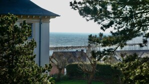 Vista sulla costa con un edificio, alberi e cielo sereno.