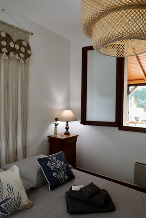 Une chambre à coucher avec un lit, une table de chevet avec une lampe, un miroir et une fenêtre.