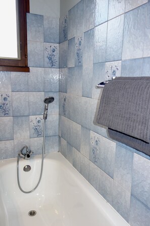 Une salle de bain avec une baignoire, une douche et un porte-serviettes.