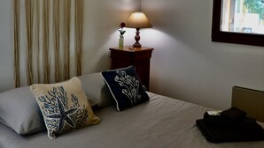 Un letto rifatto con due cuscini, una lampada da comodino e una tenda a macramè appesa.