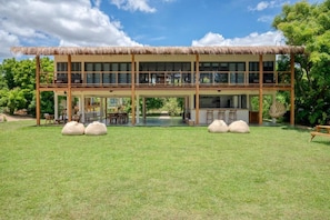 Un bâtiment à deux étages, doté d’un toit de chaume, de grandes fenêtres et d’un espace extérieur aménagé avec des sièges.