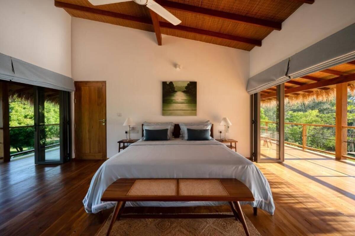 Een ruime slaapkamer met een groot bed, een bankje en een landschapsschilderij.