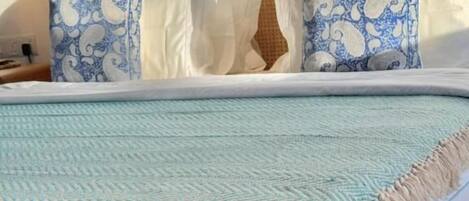 A bed with a wooden headboard, white and blue patterned pillows, and a light blue bedspread.