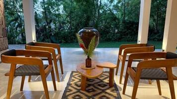 Un área de estar exterior moderna con sillas de madera y una mesa central, rodeada por un tapete estampado.