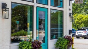 Un edificio con puerta y ventanas color turquesa, con el rótulo "Yallah".