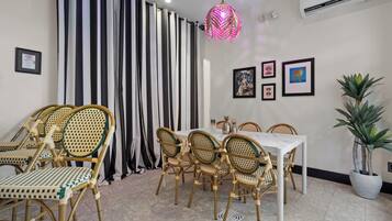 A dining area with a white table and chairs, striped curtains, and a potted plant.