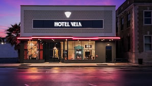 A hotel with a modern facade, a prominent sign, and a well-lit entrance. - Hotel Vela (Gulfport)