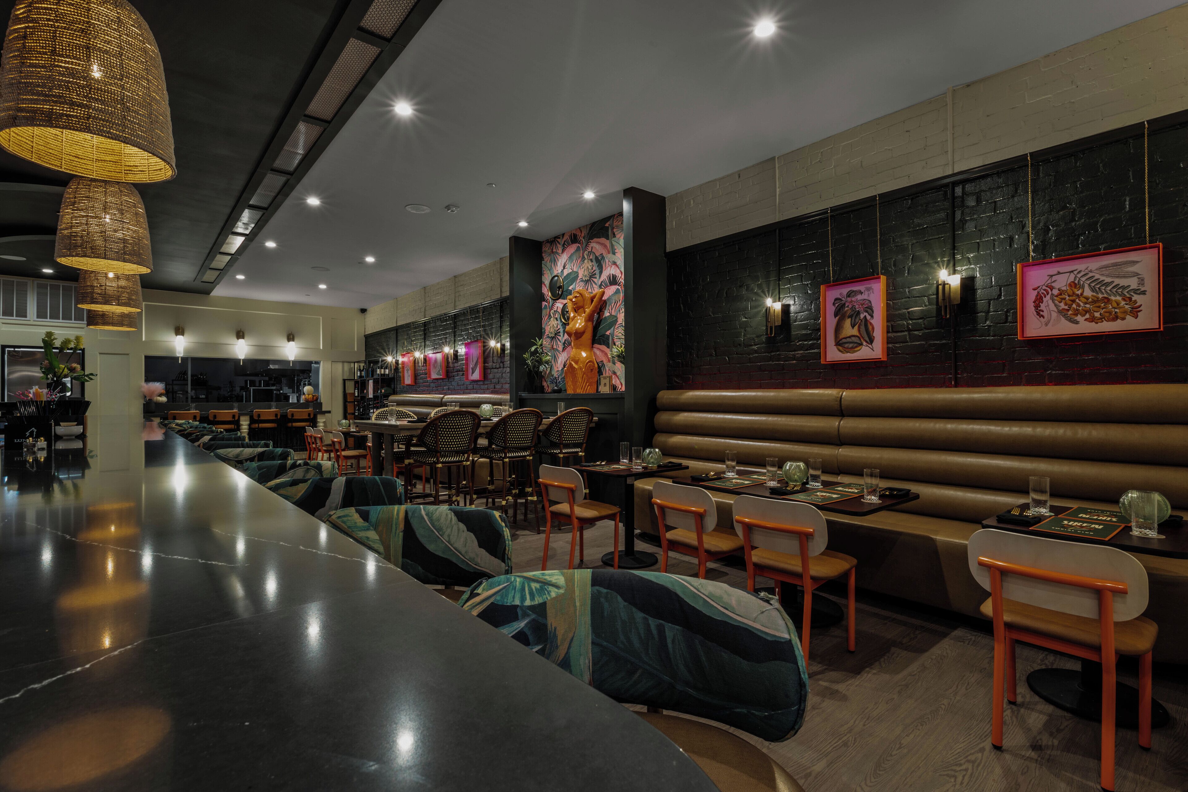A modern restaurant interior with a long counter, booths, and high ceilings.