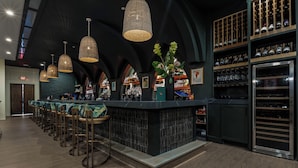 A bar area with a long counter, multiple hanging light fixtures, and a wine rack. - Hotel Vela (Gulfport)