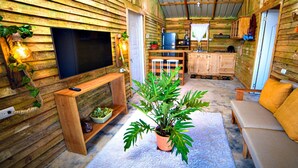 Un intérieur de chalet chaleureux avec un téléviseur, des murs en bois, un canapé et un coin repas.