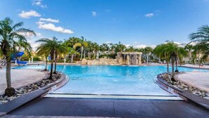 A swimming pool with palm trees and a stone structure in the center. - 4BR Townhome 6 mile to Disney (Kissimmee)