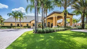 A yellow building with a covered patio and palm trees. - 4BR Townhome 6 mile to Disney (Kissimmee)