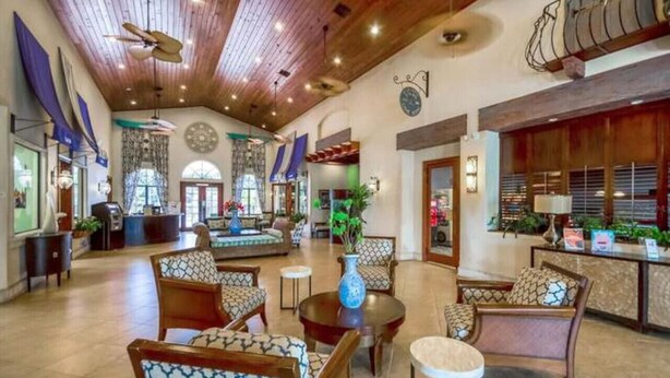 A spacious lobby with high ceilings, wooden beams, and a variety of seating arrangements including sofas and chairs. - 4BR Townhome 6 mile to Disney (Kissimmee)