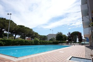 A swimming pool with tiled edges, surrounded by a brick patio.
