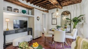 Una sala moderna con televisor, sofá, mesa de comedor y sillas.