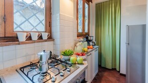 Una cocina con estufa a gas, cafetera y un tazón de vegetales.