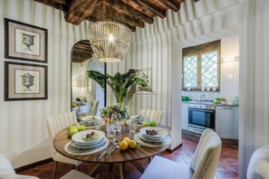 A dining area with a round table set for four, surrounded by white chairs, a hanging light fixture, and framed artwork on the wall. - Casa Genny in Lucca With 1 Bedrooms and 1 Bathrooms (Lucca)