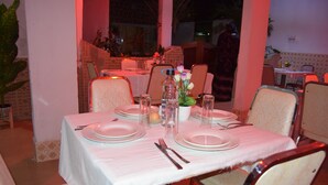 Une table à manger dressée avec des assiettes, des couverts et des verres, entourée de chaises.