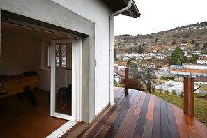 Varanda com deck de madeira dando vista para uma cidade.