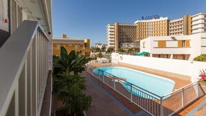 A hotel with a swimming pool, outdoor seating, and a view of the surrounding buildings. - Alsol Las Perlas (San Bartolomé de Tirajana)