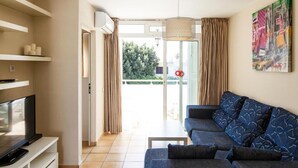 A modern living room with a sofa, TV, and artwork on the wall. - Alsol Las Perlas (San Bartolomé de Tirajana)